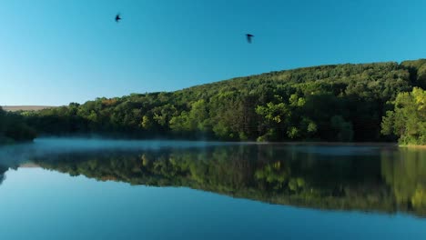 Temprano-En-La-Mañana,-Un-Dron-Bajo-Disparó-Sobre-Un-Lago-Brillante-Con-Algo-De-Niebla-3