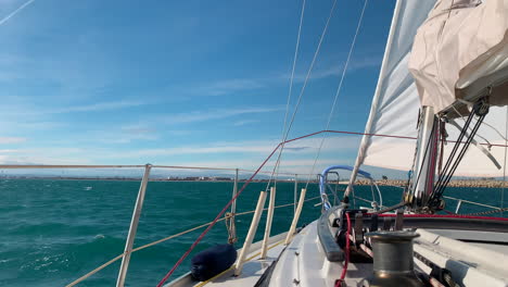 view of the front deck of a sailboat under sail near the port of valencia, spain