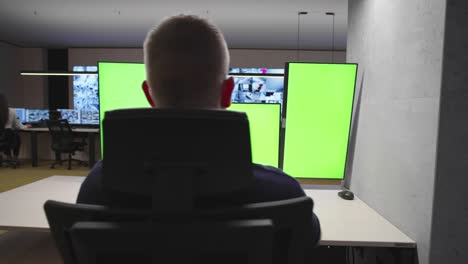 system security specialist working at system control center. room is full of green screens, chroma screen and security