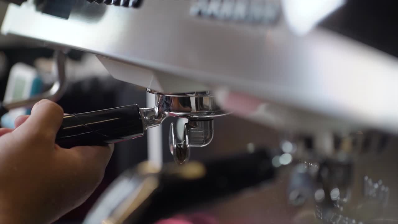 바리스타 남자가 카푸치노나 라테를 만들기 위해 커피 기계에 포타필터를 설치합니다.