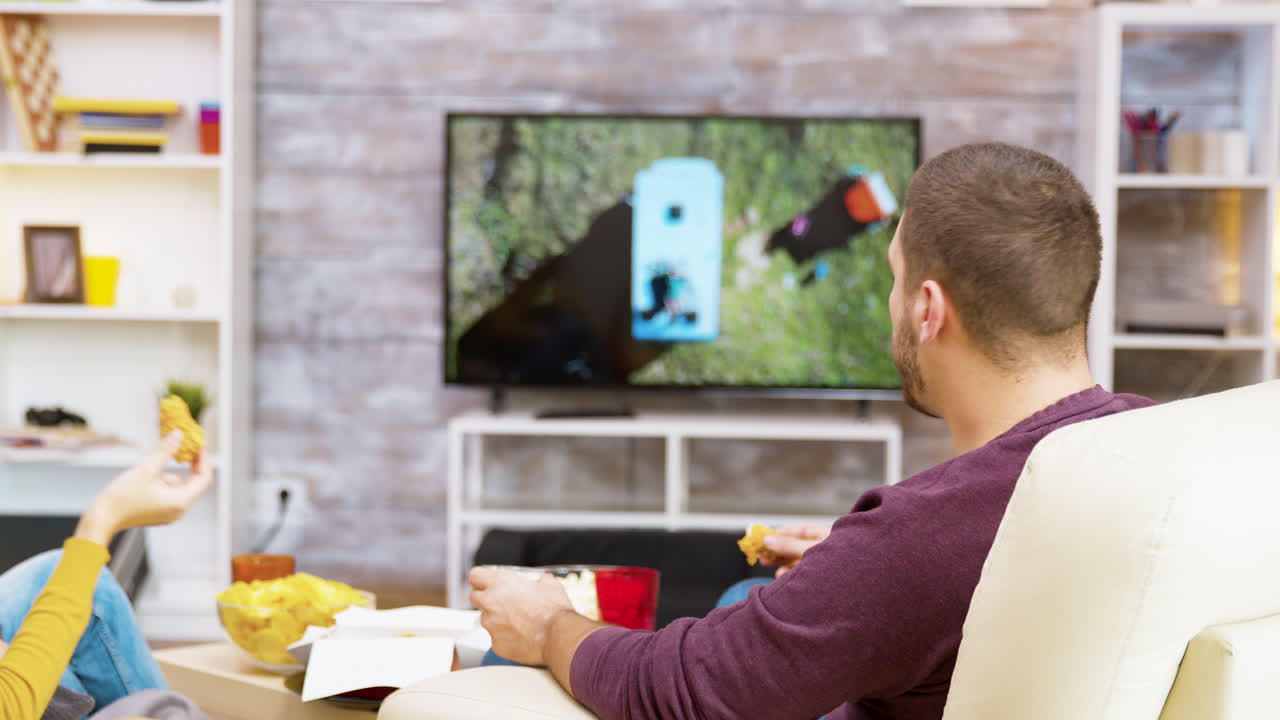 Uomo che guarda la televisione mentre mangia