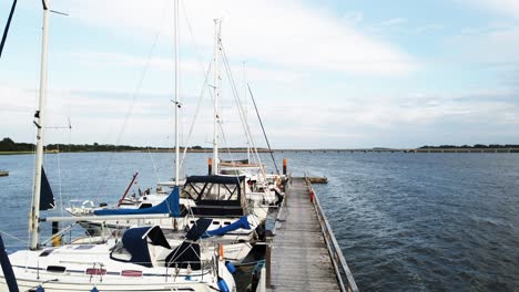 Aerial:-Going-up-a-small-harbour-with-many-sailing-boats-on-Rügen,-Germany