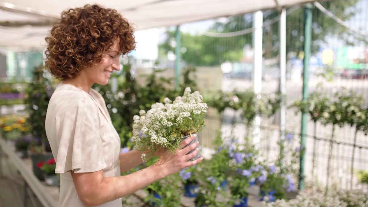 Kvinne lukter på hvite blomster på et hagesenter.
