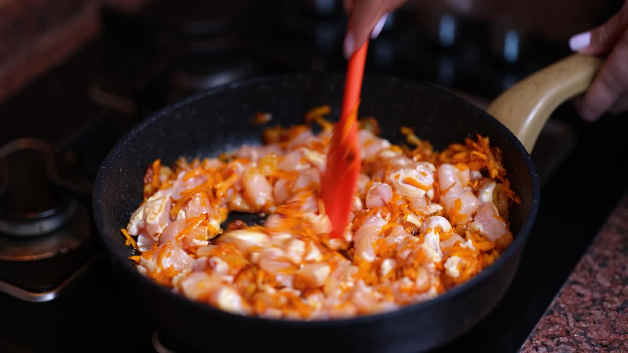 Cooking chicken and carrots in a frying pan