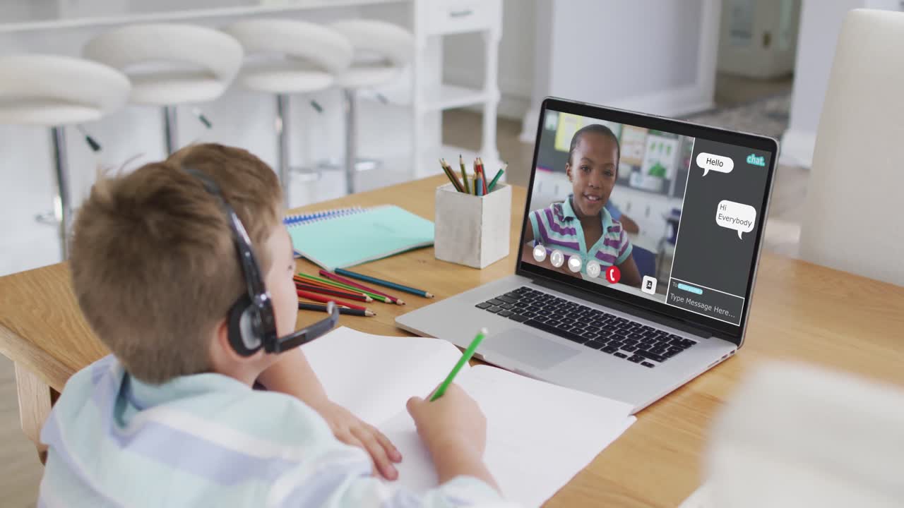 Schoolboy using laptop for online lesson at home, with school friend and web chat on screen