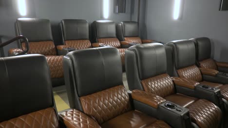 Two-rows-of-leather-movie-theater-seats-at-in-home-movie-theater,-pan