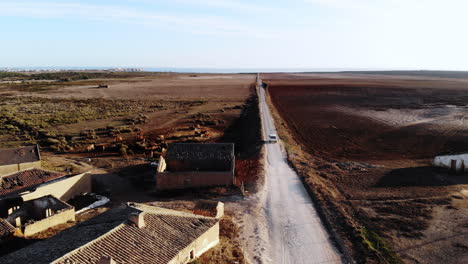 Aerial-track-shot-of-car-driving-on-country-road-during-sunny-day-in-Portugal