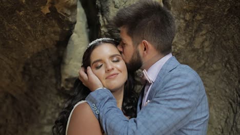 el novio con la novia de pie en la cueva de las colinas de la montaña.