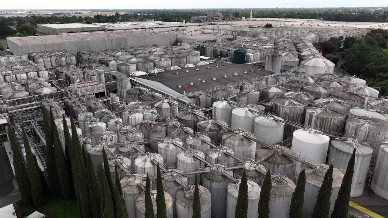 Umfangreiche industrielle Tankanlage mit silbernen Weinlagertanks bei der Gallo Winery in Modesto, Kalifornien, inklusive Verarbeitungsanlagen, an einem bewölkten Tag in den Vereinigten Staaten. Luftaufnahme.