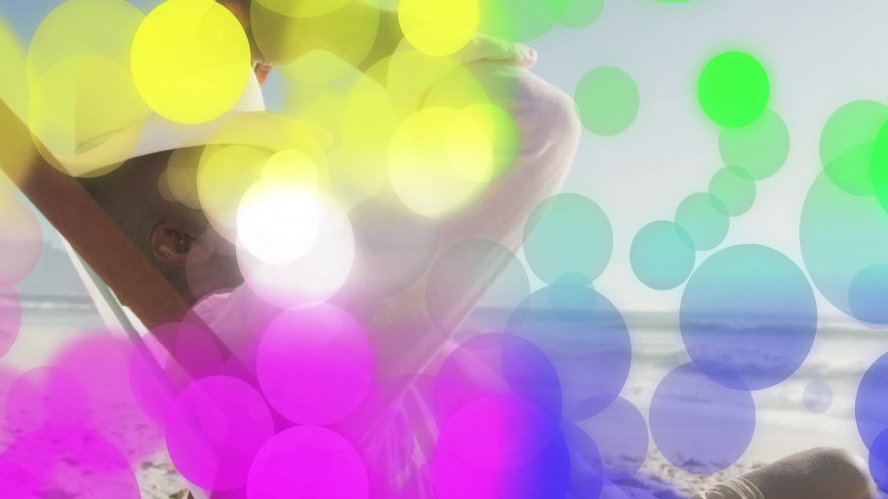 Mature man shielding eyes on sandy beach, featuring colorful bokeh overlay for marketing campaign