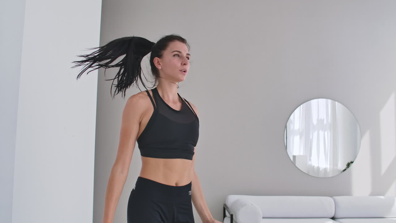 Woman doing jumping jacks at home. Sportswoman doing jumping jacks exercise at home