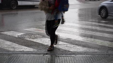 woman with children crossing street in the rain