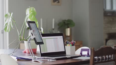 Leerer-Hausraum-Mit-Laptop-Und-Tablet-Mit-Grafiken-Auf-Bildschirmen-Auf-Dem-Tisch-In-Zeitlupe
