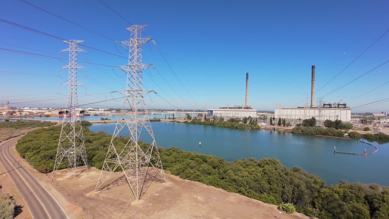 drone flying towards a power station in between power lines on a sunny day in Australia 4k 50p