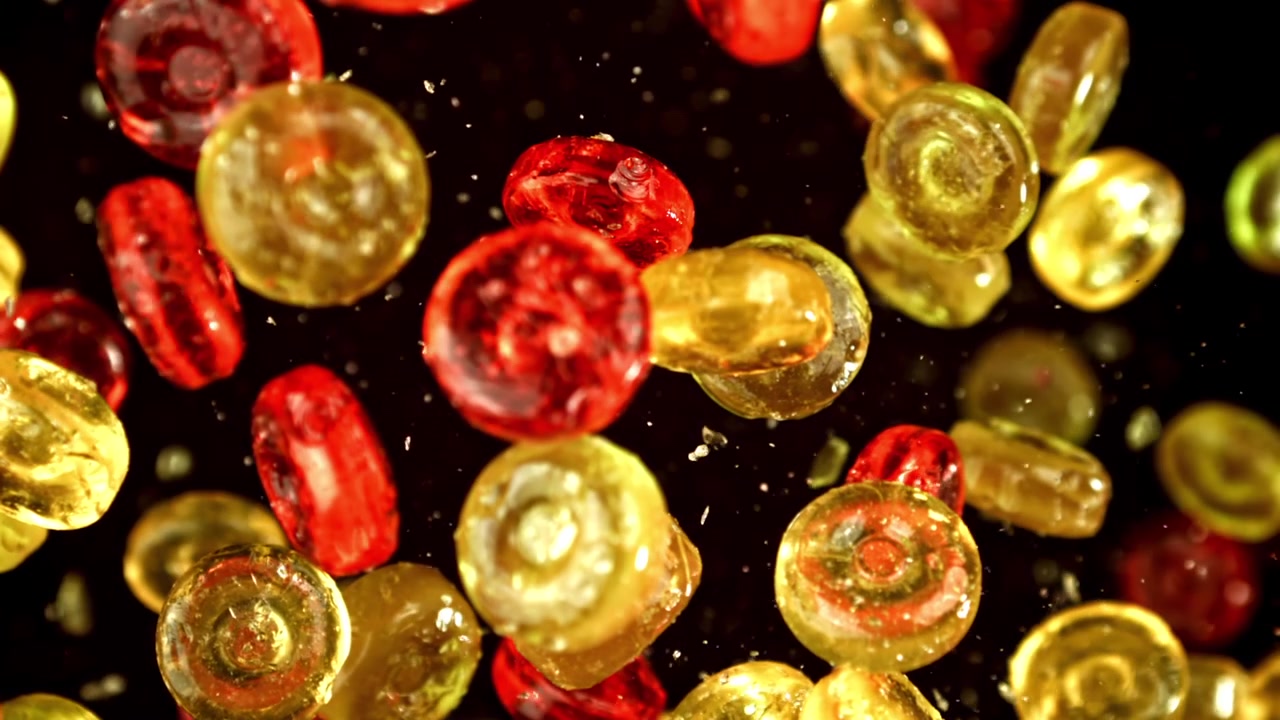 Caramelos de colores rojo y amarillo cayendo en cámara lenta