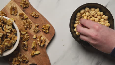 close up of hand choosing from bowls of walnuts and hazelnuts in studio