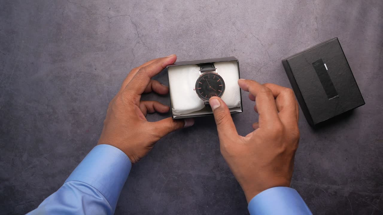 desenvase de un reloj de cuero negro con correa