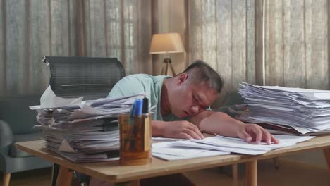 fat asian man sleeping due to working hard with documents at the office