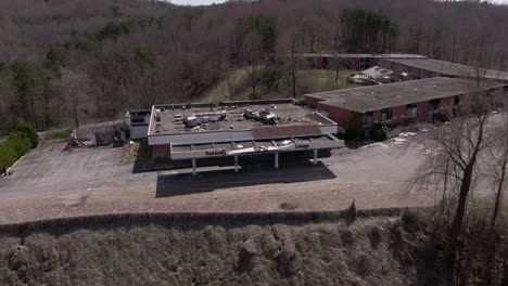 Aerial-Drone-Footage-Dollying-Forward-and-Panning-Down-of-a-Creepy-Abandoned-Hotel-and-Restaurant-on-top-of-a-Hill