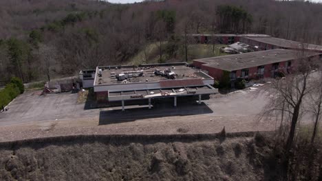 imágenes aéreas de drones que avanzan y se desplazan hacia abajo de un espeluznante hotel y restaurante abandonados en la cima de una colina