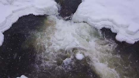 Vista-En-Cámara-Lenta-De-Una-Pequeña-Cascada-Helada-Durante-Una-Tormenta-De-Nieve-De-Invierno