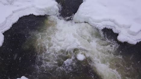 vista en cámara lenta de una pequeña cascada helada durante una tormenta de nieve de invierno