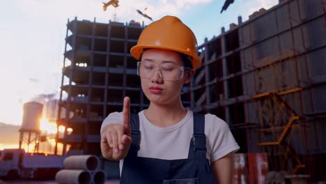 close up of asian woman worker wearing goggles and safety helmet disapproving with no index finger sign while standing at construction site