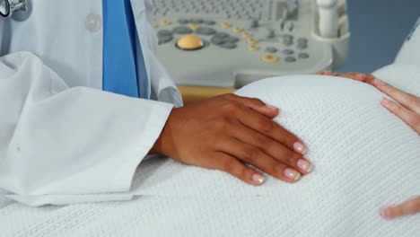 mid section of doctor comforting pregnant woman