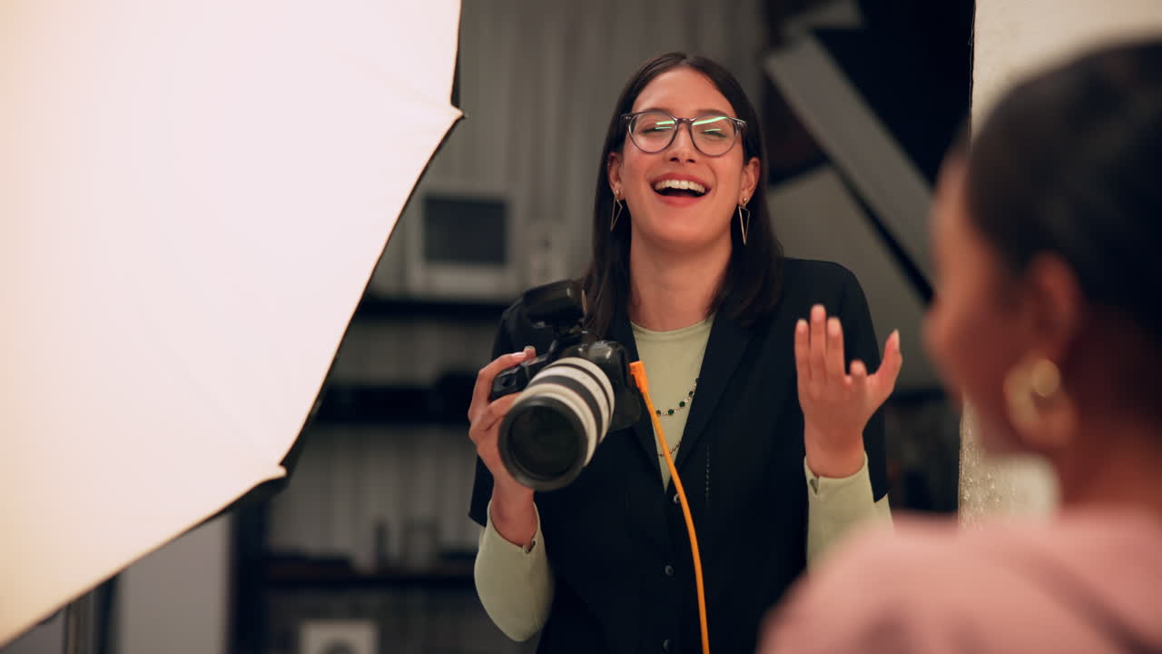 Una fotografa in uno studio che scatta foto a una modella.