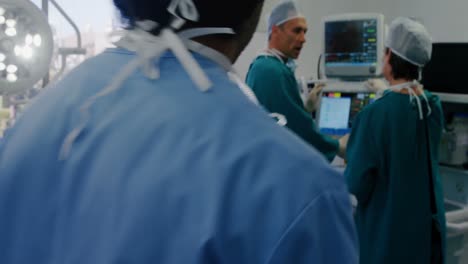 Surgeon-using-digital-tablet-while-colleagues-interacting-in-the-background