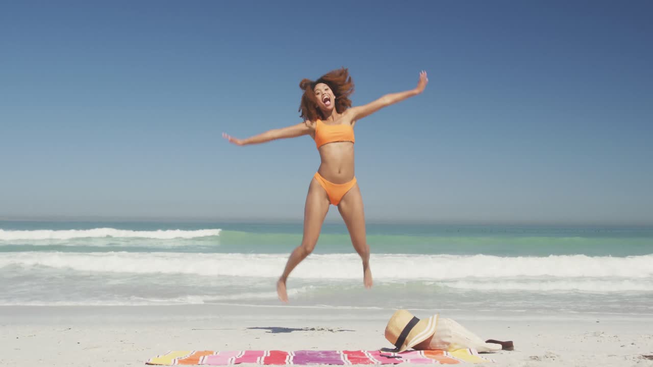 African american woman jumping at beach