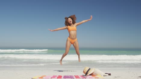 african american woman jumping at beach