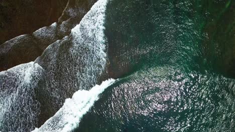 overhead drone shot of beach waves with clear water and visible the coral rocks