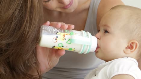 Mutter-Füttert-Ihre-Kleine-Tochter-Mit-Einer-Flasche