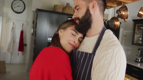 video de una feliz pareja caucásica abrazándose en la cocina