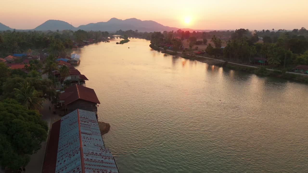Sunset Aerial View over Laotian River, 4000 Islands Landscape, traditional village houses with burning smoke Laos