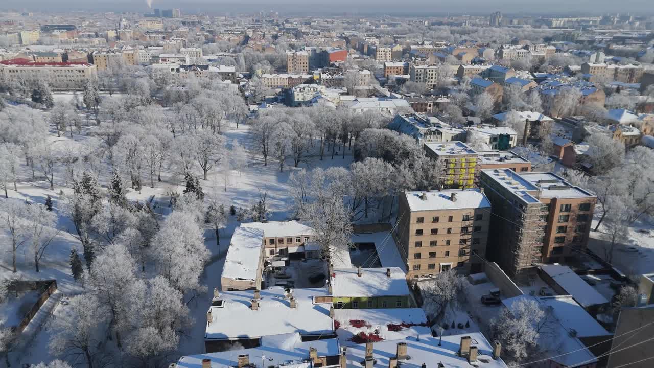 Letonya'nın başkenti Riga'nın, güneşli, soğuk bir kış gününde, karla kaplı çatılar, tüten bacalar, parlak mavi gökyüzü ve berrak atmosferik ışıkla muhteşem bir havadan görünümü.