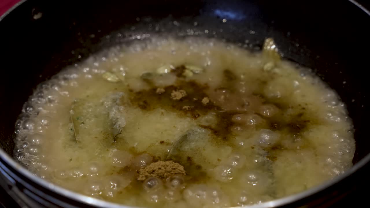 La polvere di curry viene delicatamente spolverata su una pentola di cipolle che sobbollono, evocando l'essenza della maestria culinaria e della meticolosa preparazione del cibo