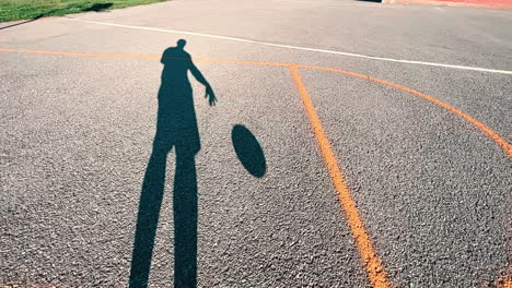 Long-shadow-bouncing-a-basketball-outdoors-at-dusk