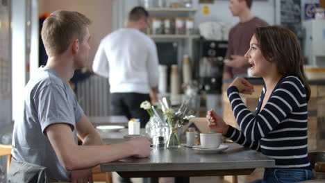 volwassen koppel praat aan een tafel in een koffiewinkel, zijweergave