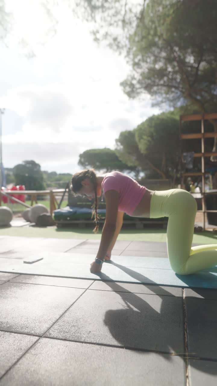 Woman in activewear exercising outdoors on a mat