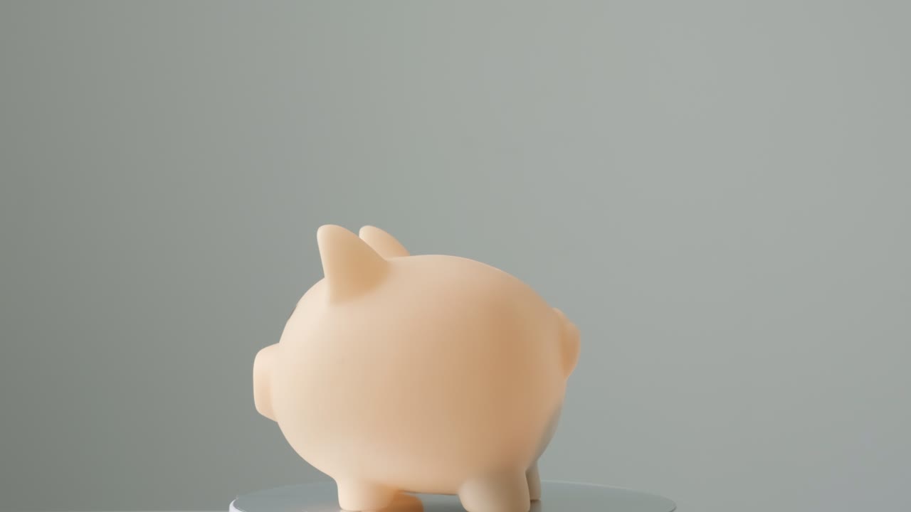 灰色の背景で回転するピンクの貯金箱。年金、休暇、通貨、貯蓄、財務会計