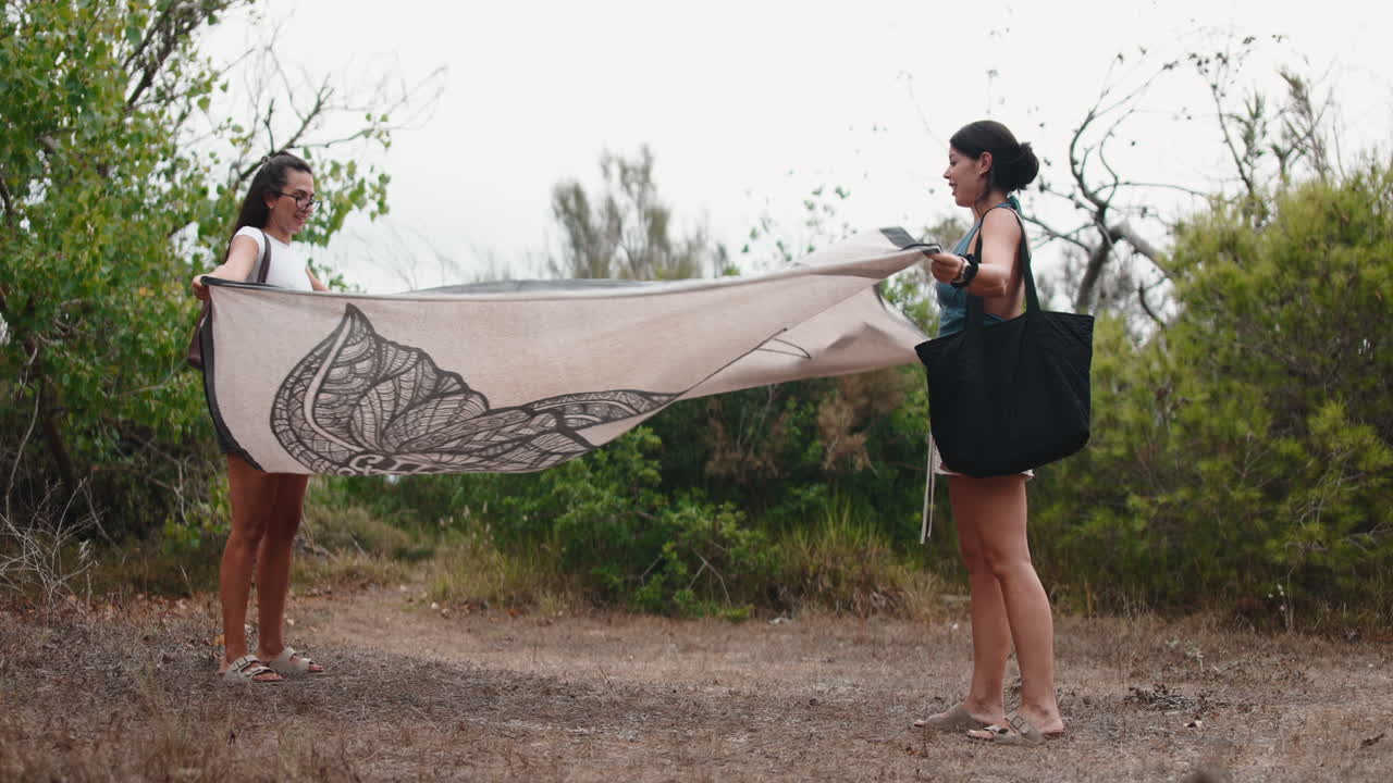 Two Women Spreading a Beach Blanket Outdoors