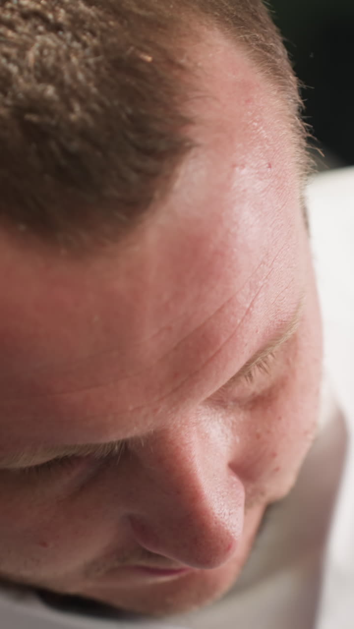 그가 머리에 손을 고 잠을 자는 동안 기술자의 얼굴을 근접적으로 볼 수 있습니다.