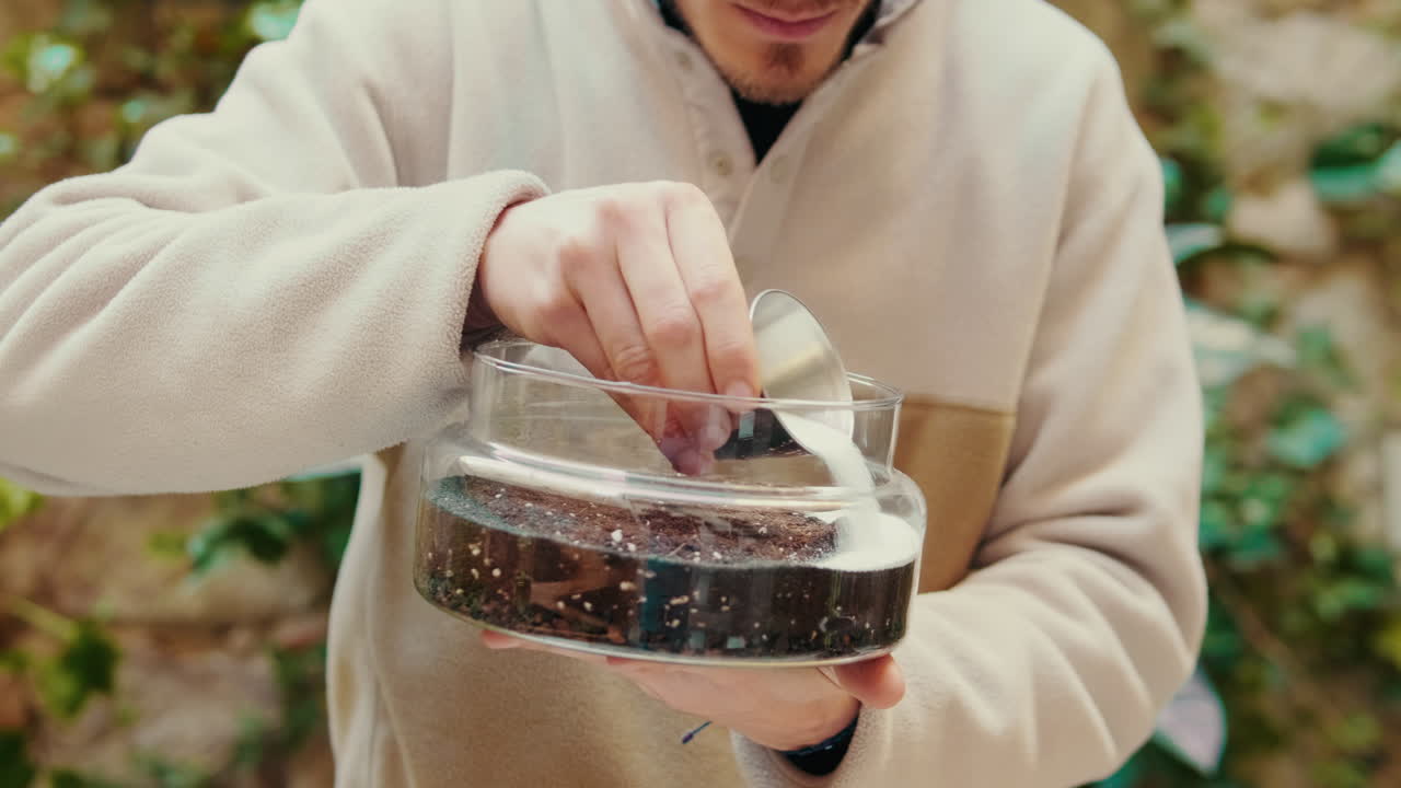Uomo che versa sabbia in un contenitore di vetro per terrario