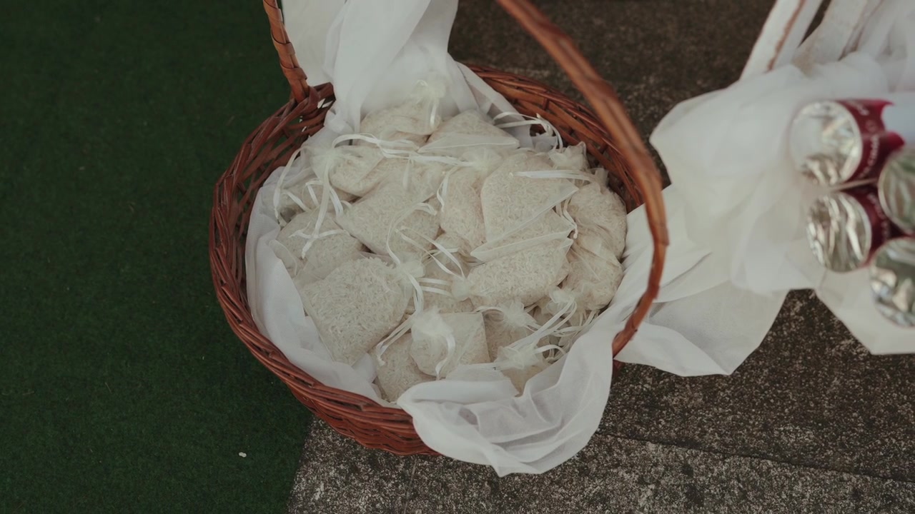 Piccoli sacchetti di stoffa legati rivestono un panno bianco all'interno di un cesto di vimini a un raduno all'aperto