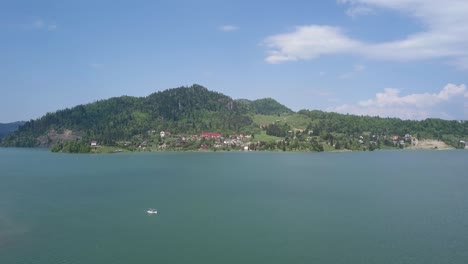 Antena-Hacia-Arriba-Del-Lago-Con-Bosques-En-El-Fondo-Y-Cielos-Azules-Claros