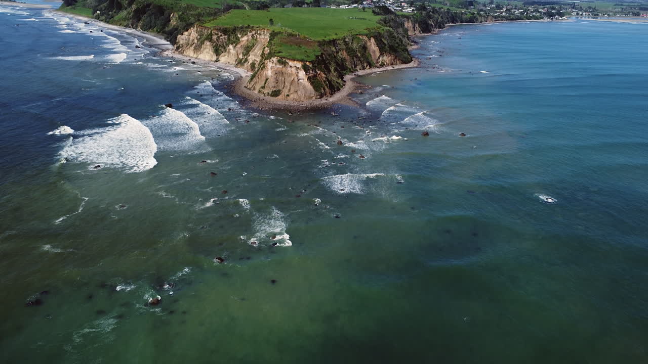 olas espumosas salpicando en la orilla pedregosa de la playa de maketu en la isla norte, nueva zelanda - toma aérea de drones