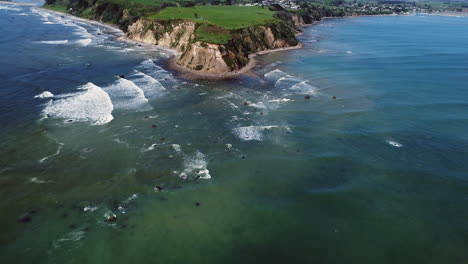 Olas-Espumosas-Salpicando-En-La-Orilla-Pedregosa-De-La-Playa-De-Maketu-En-La-Isla-Norte,-Nueva-Zelanda---Toma-Aérea-De-Drones