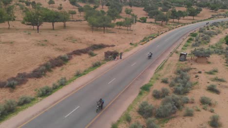 aerial tracking shot of two motorbikes on remote road highway through tharparkar in sindh